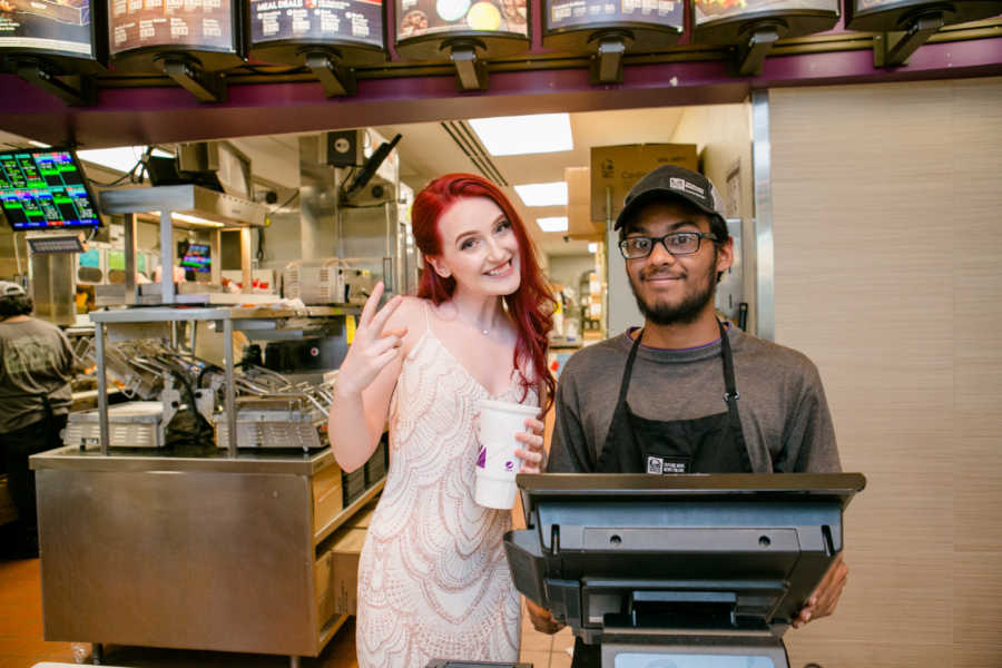 Teen stands behind taco bell register in her prom dress with worker