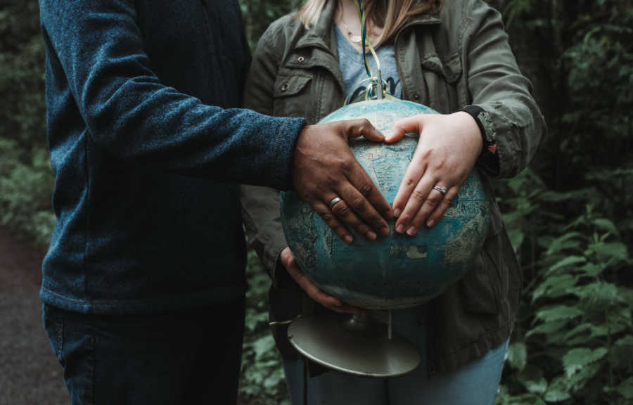 Soon to be adoptive parents hold a globe and make shape of heart with their hands over India