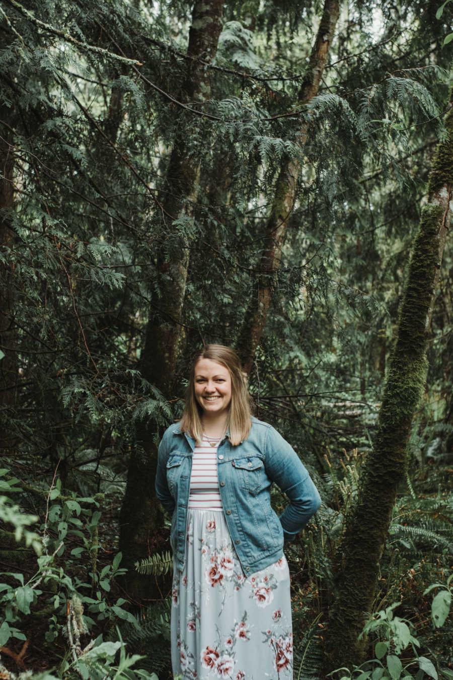 Woman who will adopt a child from India, standing and smiling in forest