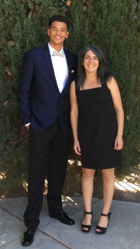 Teen whose mom kicked him out of her house stands in suit smiling with foster mom