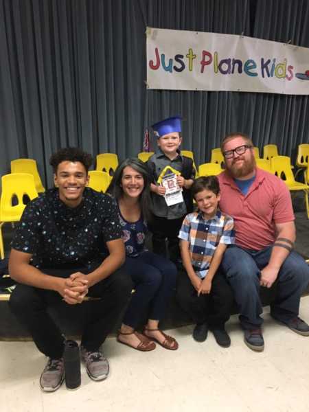 Young man sits with foster parents and their two young boys