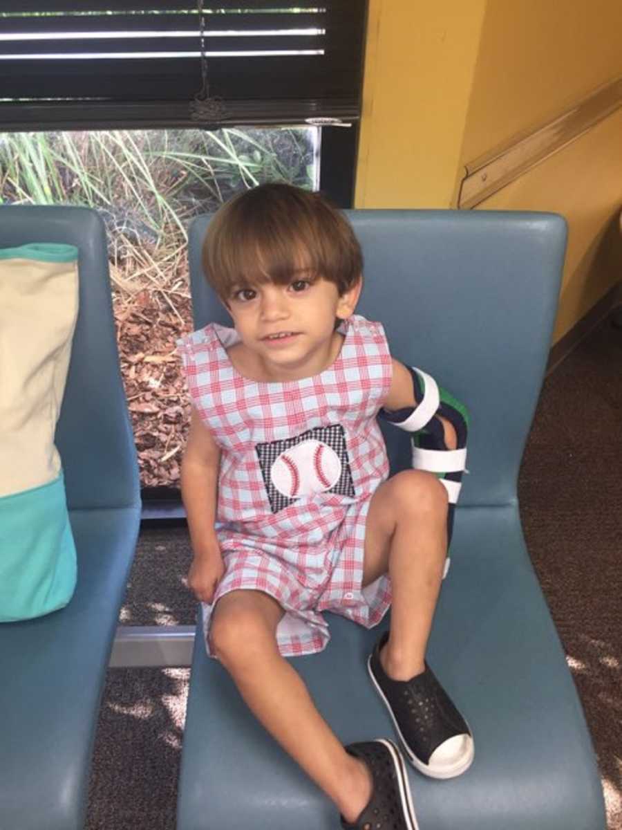 14 month old boy with mild cerebral palsy due to hemiplegia sitting in chair with cast on arm 