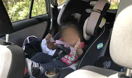 Blurred out face of baby in car seat who was left in hot car for hours but saved by officer