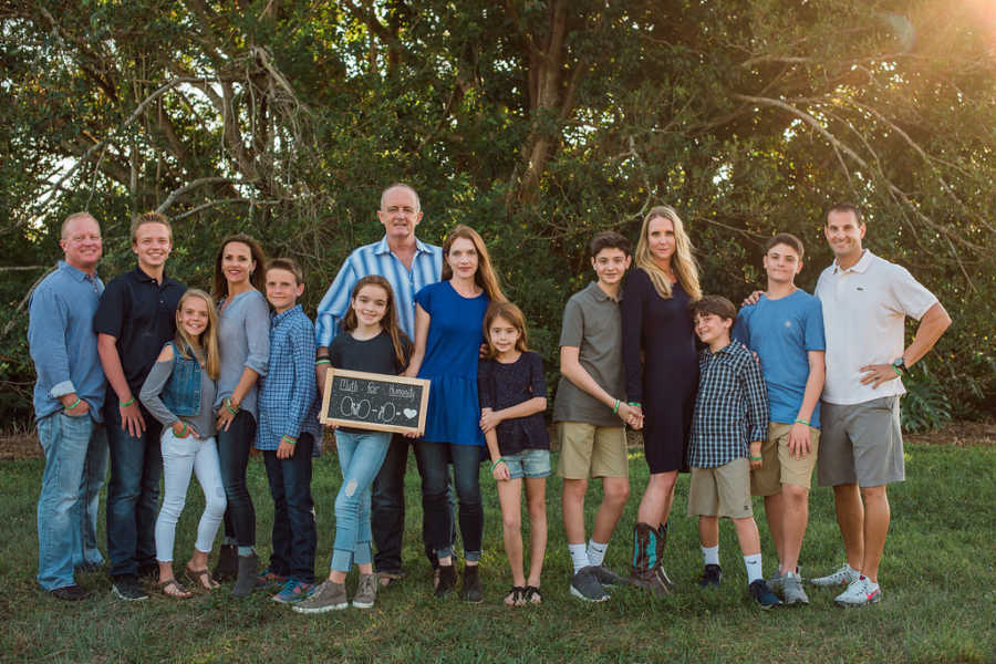 Man who needed kidney transplant stands with his family beside donor and her family and another family