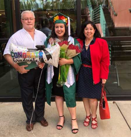 Young woman at college graduation with parents whose scholarships were taken away as she was undocumented citizen