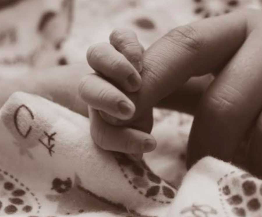 Mother touches fingers of still born baby