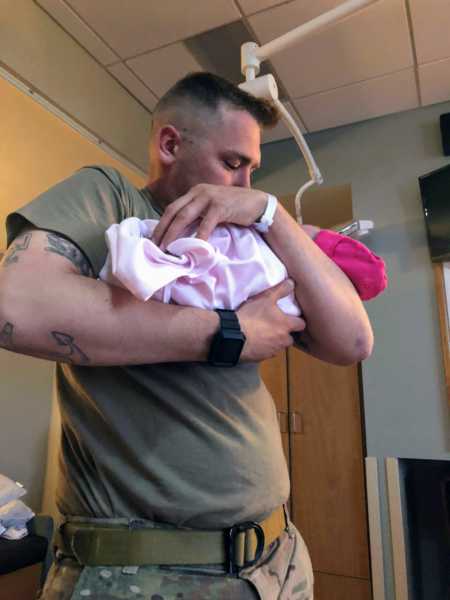 Soldier father who missed daughter's birth by an hour holds newborn in his arms in hospital