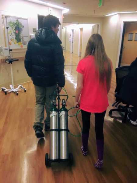 23 year old with cystic fibrosis walks in hospital with young man who is pulling her oxygen tank
