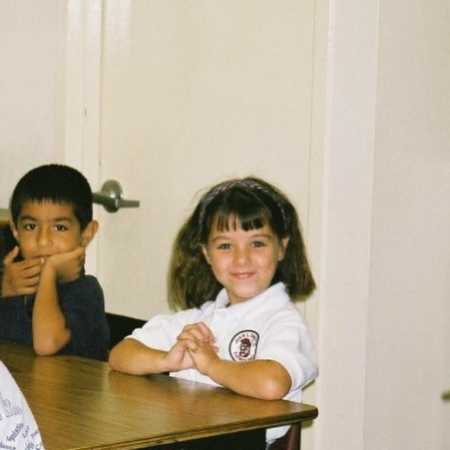 Young woman who immigrated to America when she was five years old sitting and smiling in classroom