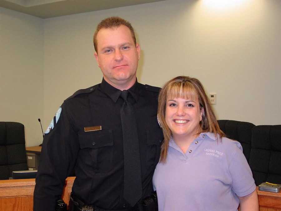 Wife stands beside cop husband smiling who has since passed from pancreatic cancer