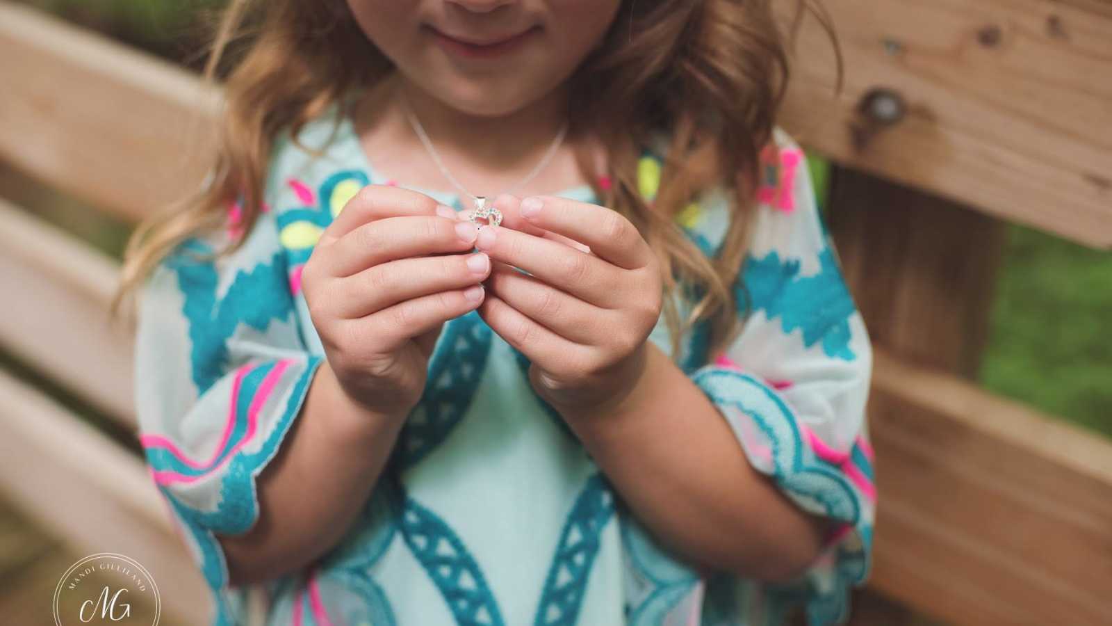 Toddler holds necklace mother's fiancee gave her at proposal