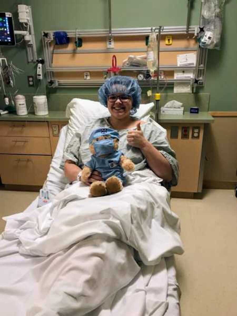 girl sits in hospital bed with stuffed bear