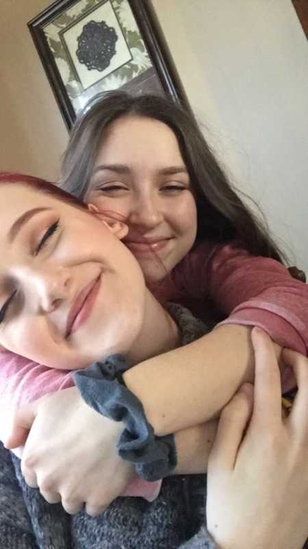 Teen girl smiling in selfie with girlfriends arms wrapped around her neck