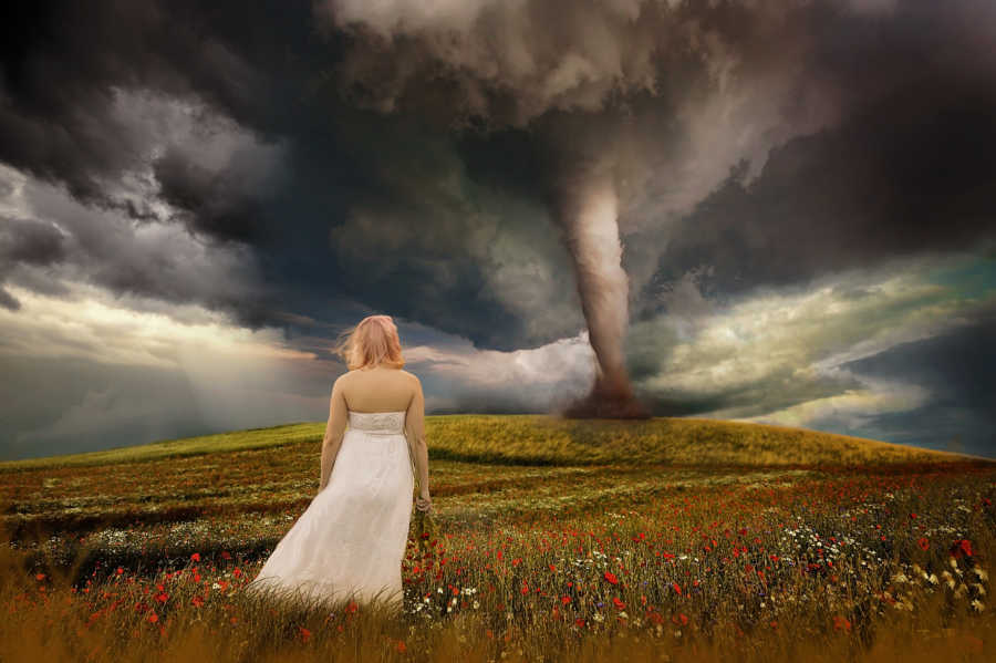 Woman with Diminished Ovarian Reserve (DOR) stands in field looking at animated tornado in distance