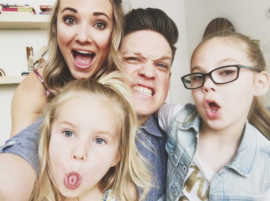 Mother smiles in selfie with her husband and two daughters