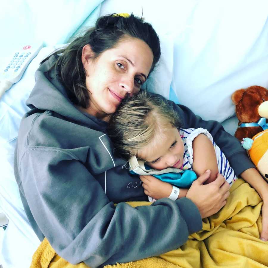 Mom battling mental health problems cuddles with her daughter in a hospital bed