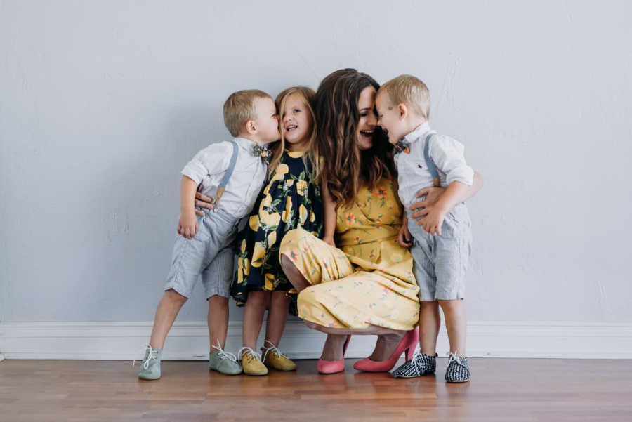 Mom takes candid photo with three children while they wear yellow and blue color-coordinated outfits