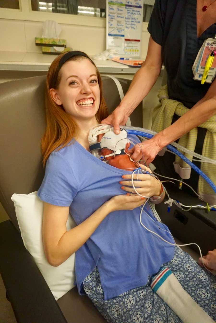 A mom holding her newborn baby who has a number of tubes connected.