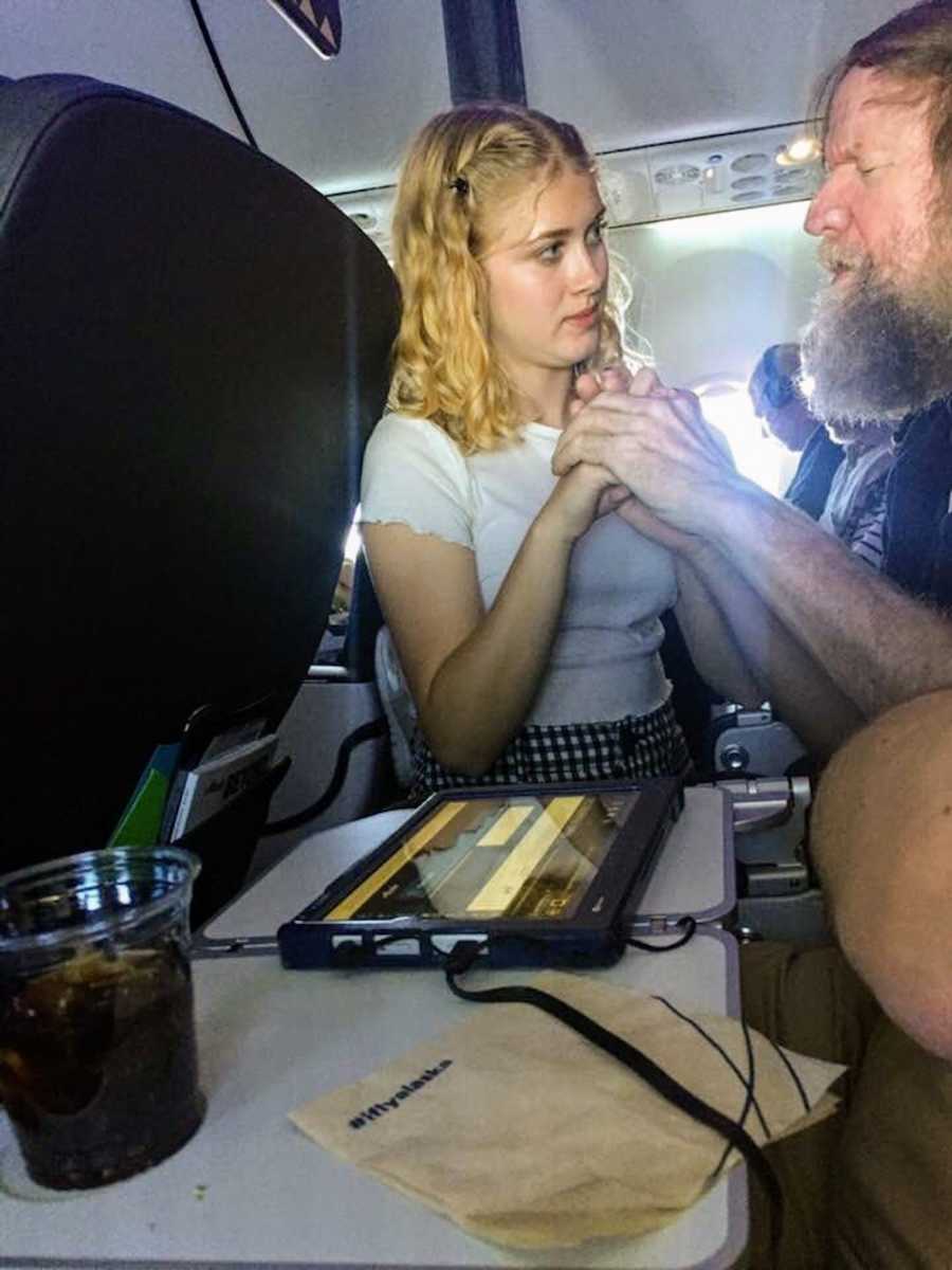 A deaf and blind older man holds a young girl's hands in his