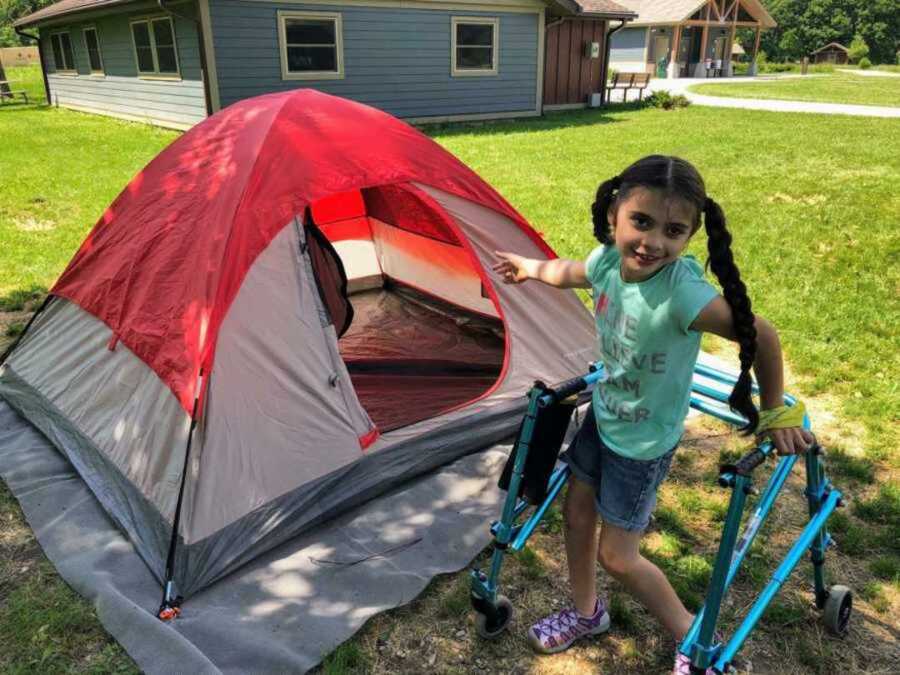 Disabled girl standing next to red and white tent