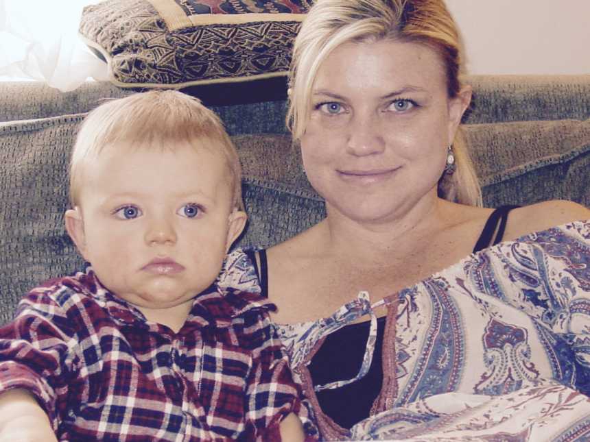 A mom sitting on a couch with her toddler son who is wearing a plaid collared shirt.