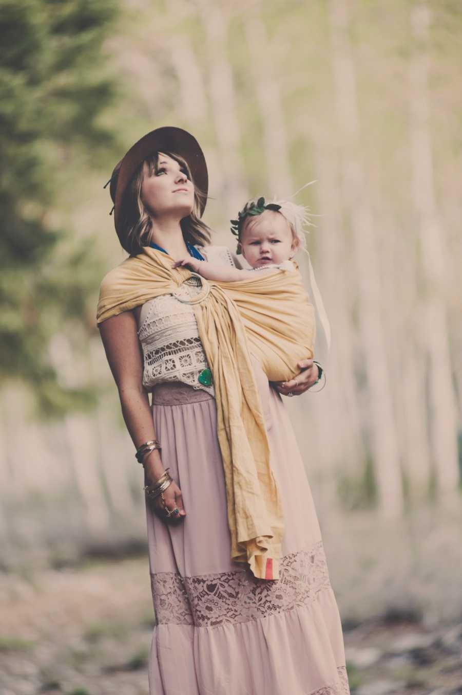 Woman who struggles with PTSD stands outside with daughter swaddled to her chest