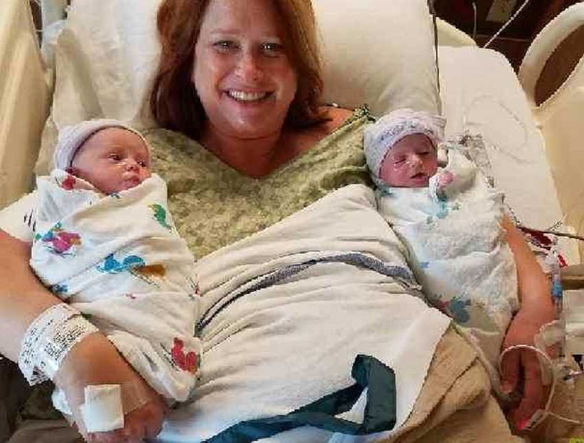 Surrogate grandmother smiles for a photo while holding the twins she just gave birth to