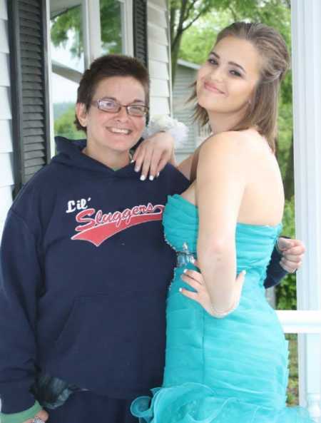 Mom and daughter smile for a photo while daughter is dressed for school dance