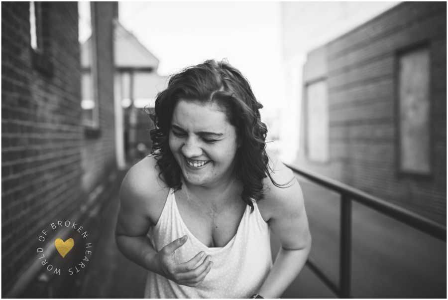 Woman embracing scars from heart surgery laughs during self-love photoshoot