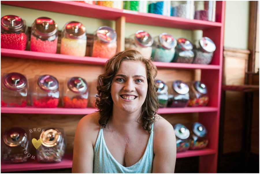 Woman born with heart defect smiles for a photo with jars of candy behind her