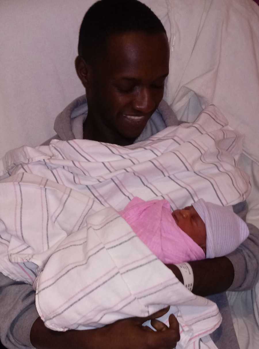 Man smiles down at his newborn daughter in the hospital