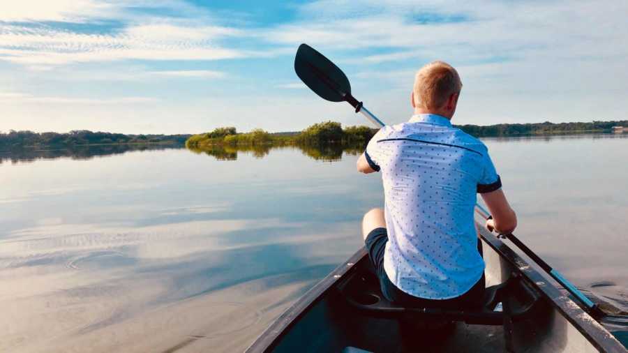 Man paddles in a kayak in a gorgeous lake setting
