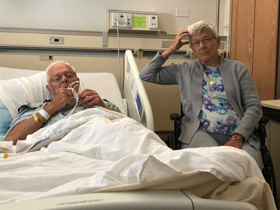 Woman with dementia sits by her husband in the hospital