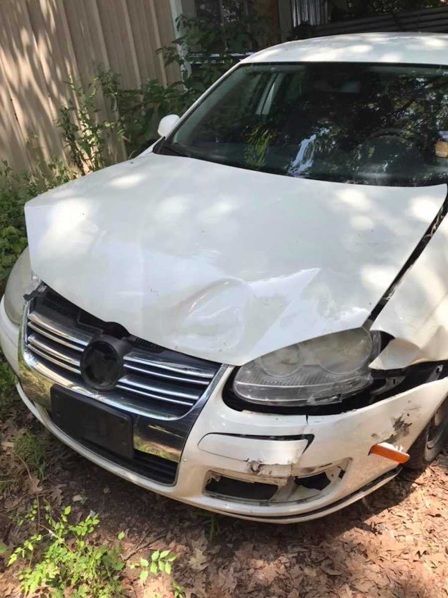 Woman takes a photo of damaged car hood after husband and baby got into a car accident
