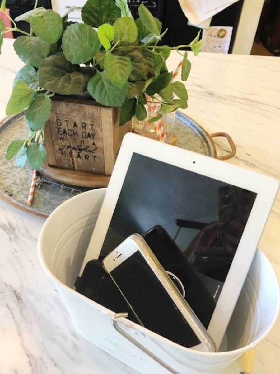 Mom takes photo of a bucket filled with everyone's phones and iPads to enjoy technology free time together