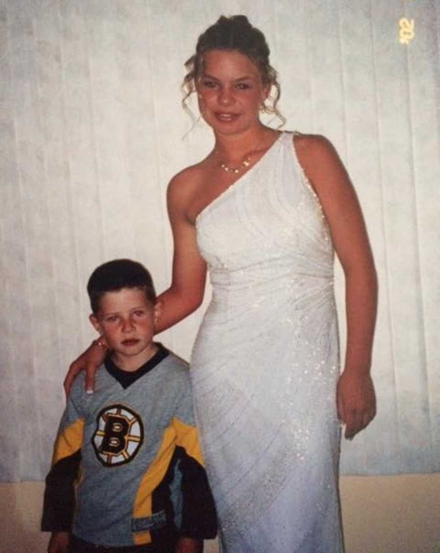 Teen girl dressed for prom poses for a photo with her little brother