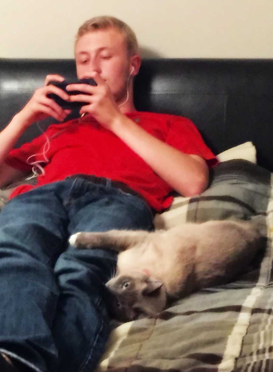 Mom snaps a photo of her college-aged son laying on the couch while using his cellphone