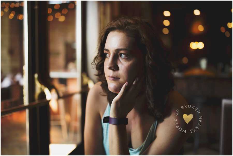 Woman raising awareness of heart defects looks serious while staring out of the window of a coffee shop