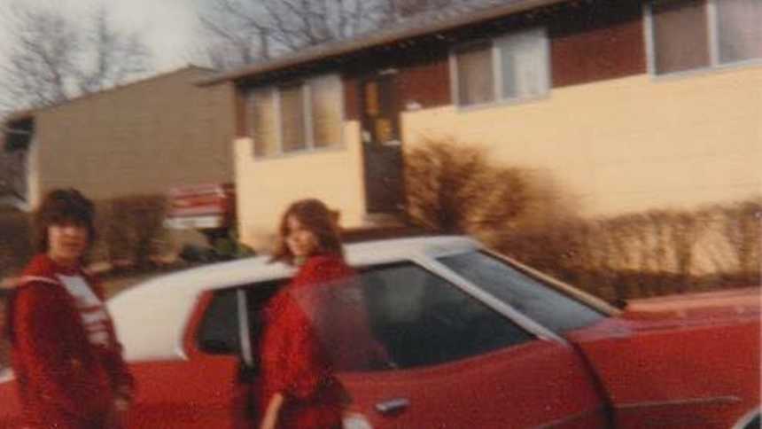 High school sweethearts look caught off-guard while getting out of a red car together