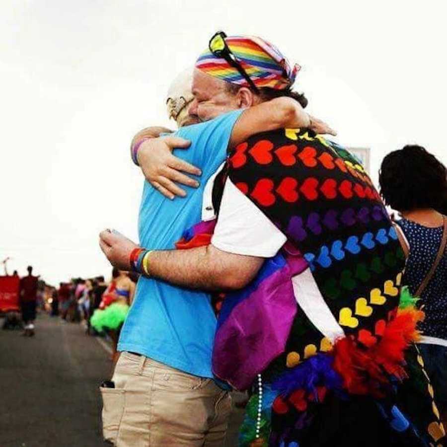 Two people embrace while celebrating love at an LGBTQ+ Pride Parade