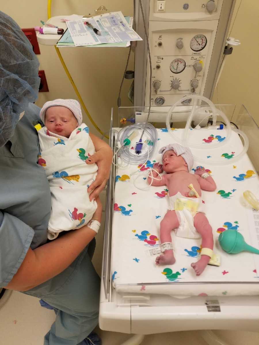 Mom holds one of her twins next to her other twin in the NICU
