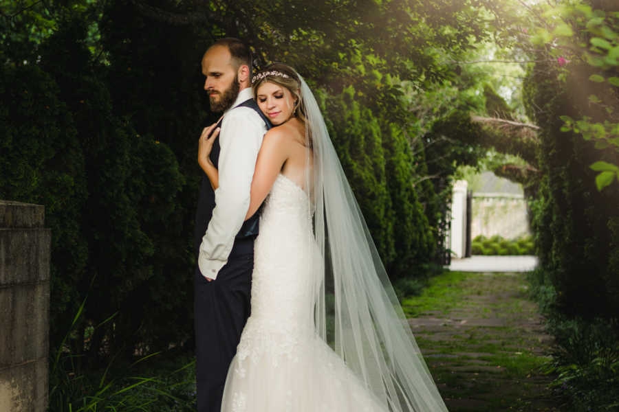 Woman hugs her husband from behind during wedding photoshoot