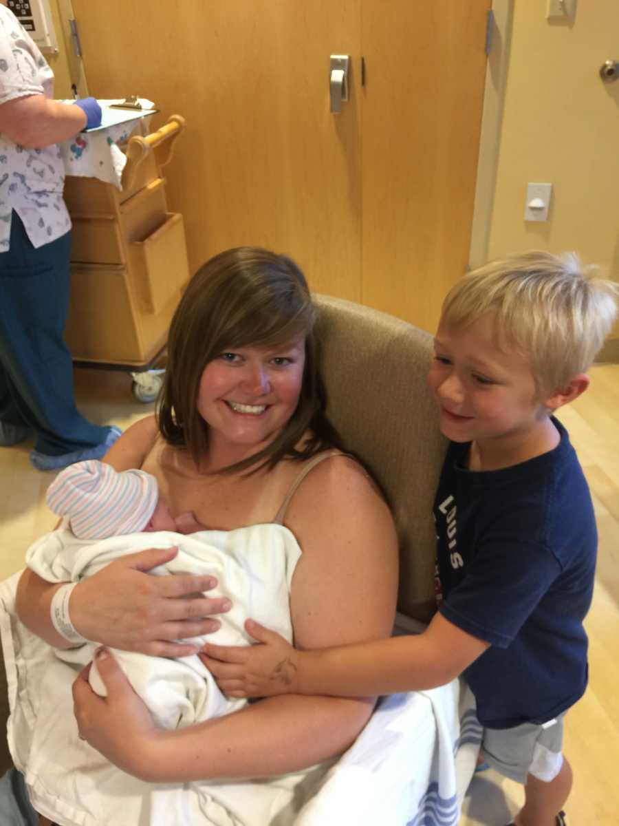 Mom smiles for a photo while her son meets her newborn twins