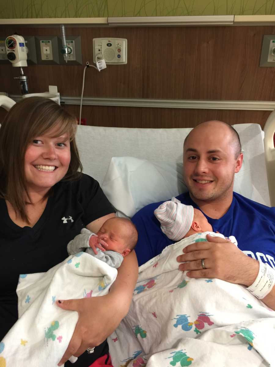 Couple smile for a photo while holding their newborn twins