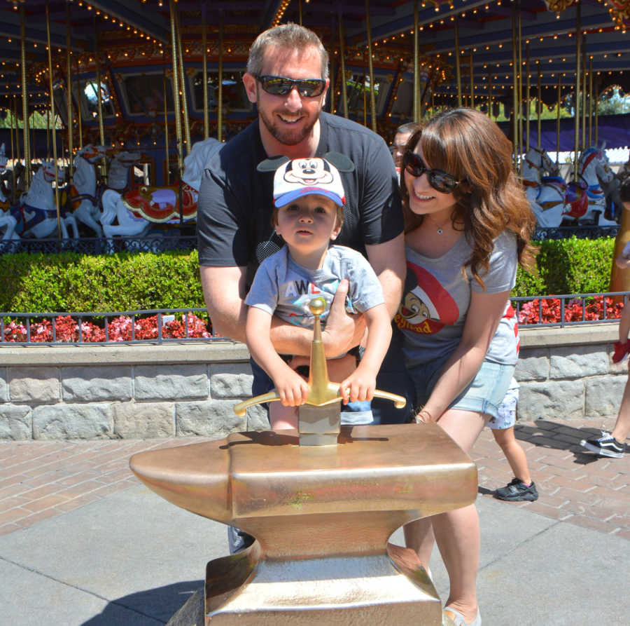 Family of three pose for a photo together while at a Disney theme park 