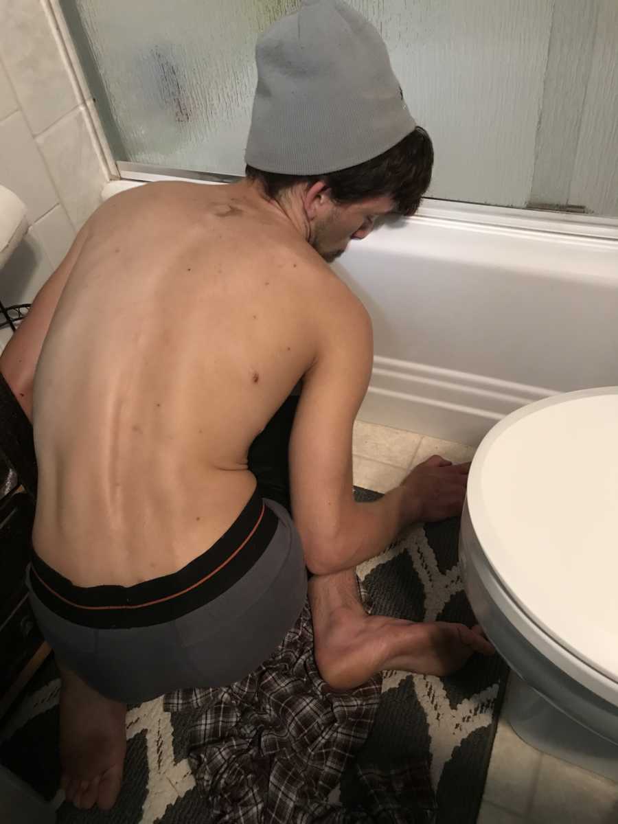 Young man struggling with drug addiction passes out on the bathroom floor with his face against the tub