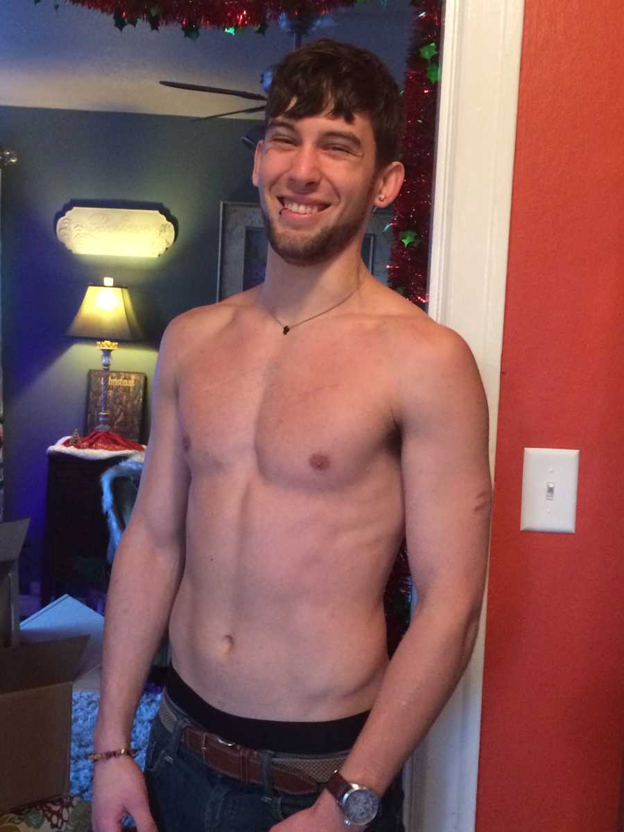 Man who struggled with drug addiction stands shirtless in doorway smiling