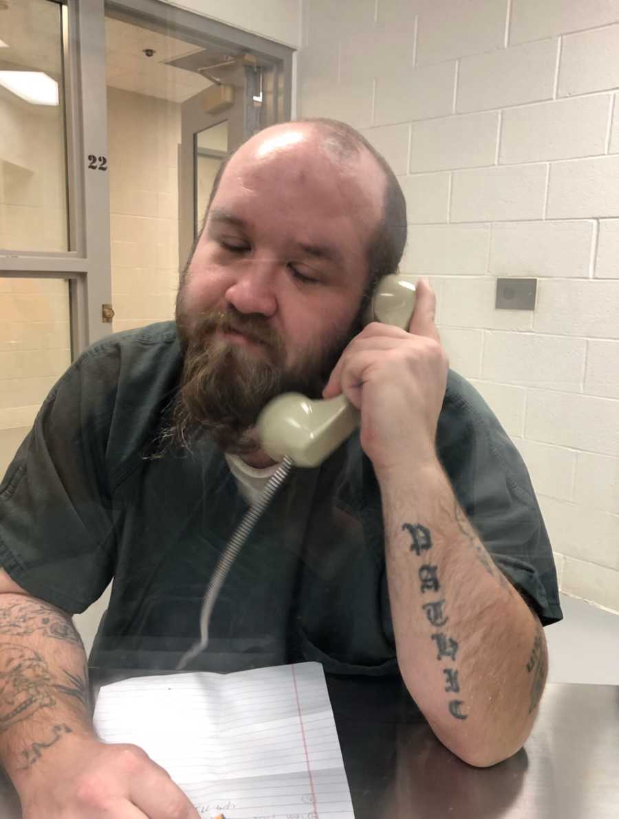 Man battling drug addiction talks on a the phone with a loved one during visitation hours in prison