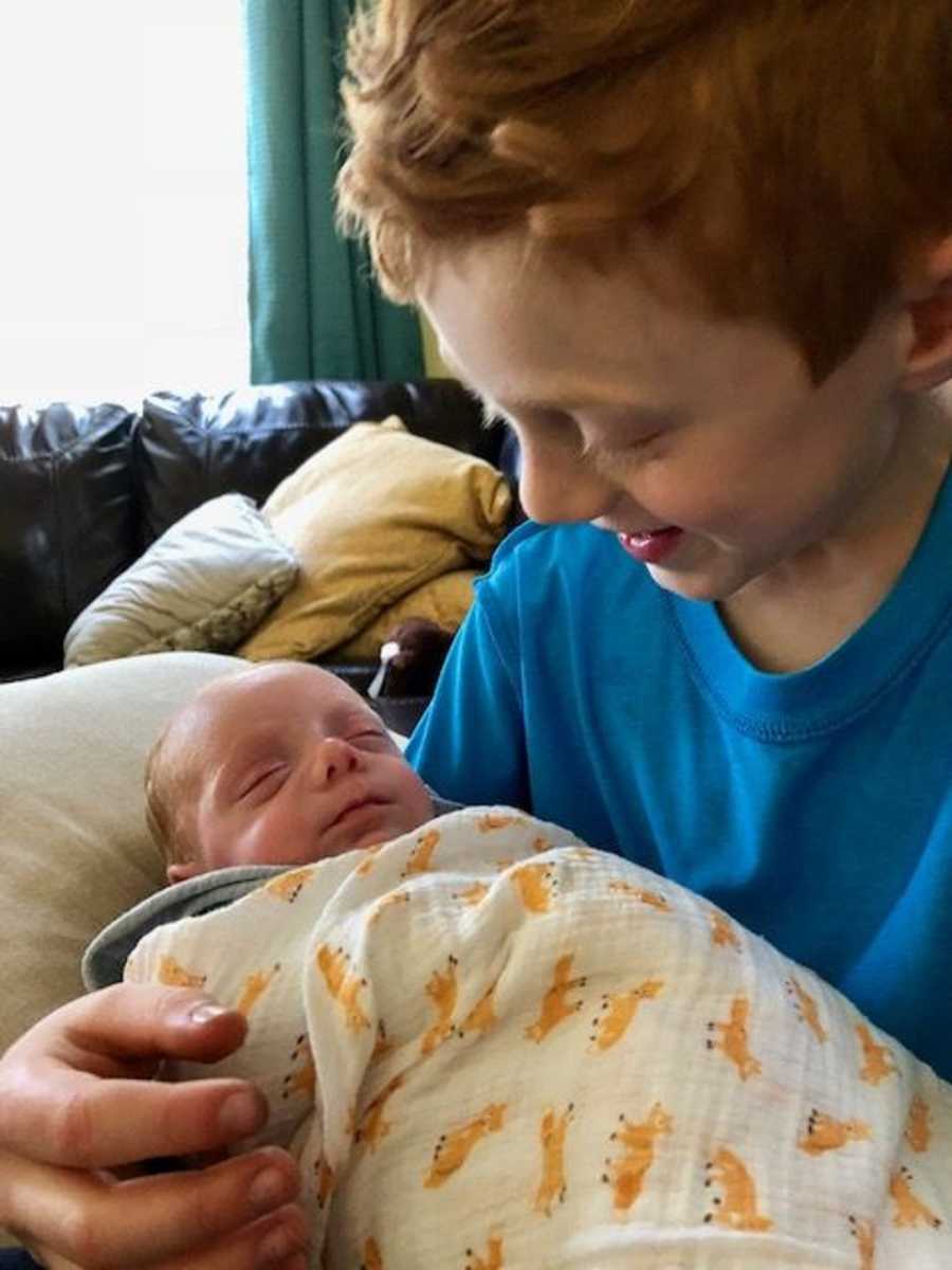Big brother smiles down at his sleeping baby brother