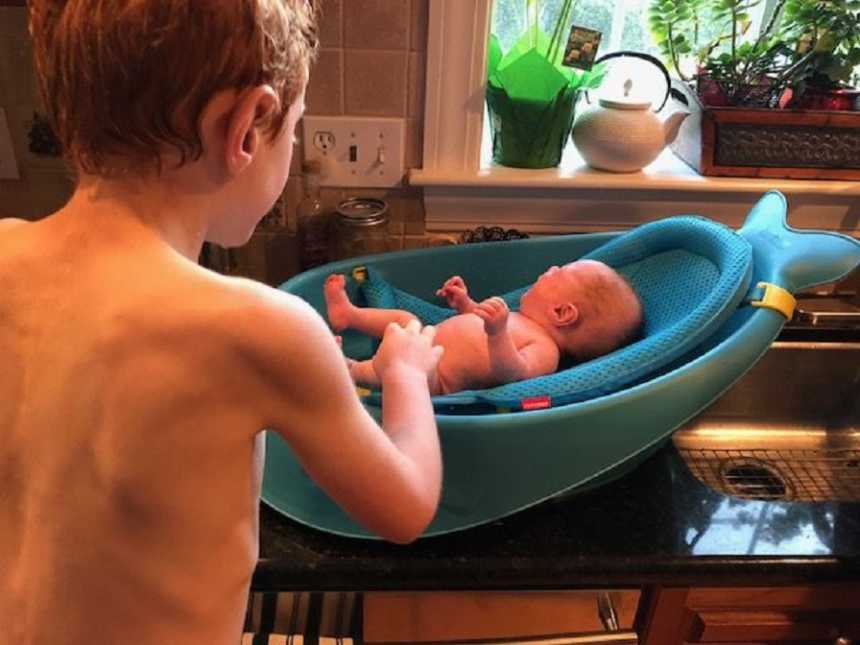 Big brother helps bathe his newborn baby brother